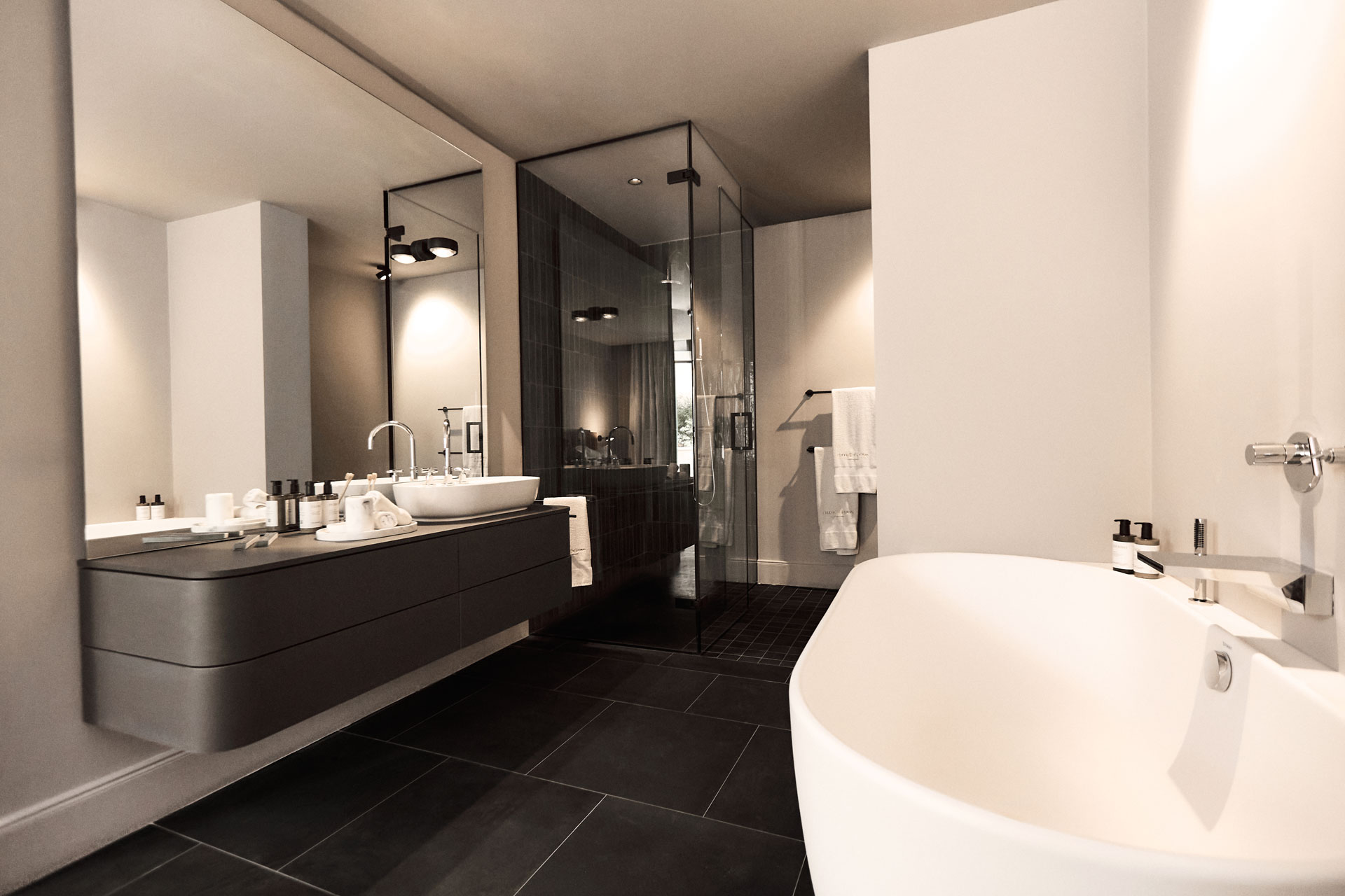 Baño con bañera exenta y suelo oscuro